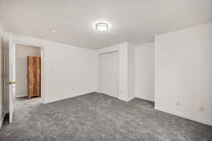 Unfurnished bedroom featuring dark carpet and a closet