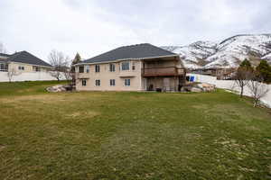 Back of house featuring a fenced backyard, a balcony, a mountain view, and stucco siding