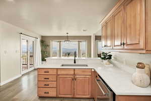 Kitchen featuring a peninsula, stainless steel dishwasher, light stone countertops, light wood finished floors, and a mountain view