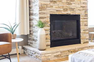 Detailed view of a fireplace with raised hearth, wood finished floors, and a baseboard heating unit