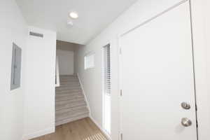 Staircase with wood finished floors and electric panel