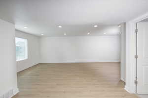 Empty room with light wood-style flooring and recessed lighting