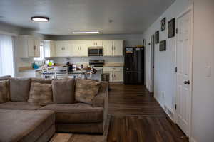 Living area with dark wood-type flooring and baseboards