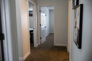 Corridor with baseboards and dark carpet
