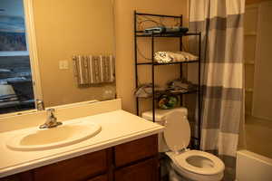 Full bath with shower / bath combo with shower curtain, vanity, and a textured wall