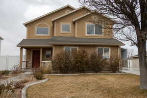 Traditional-style home with a shingled roof, stucco siding, and covered porch
