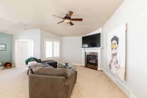 Living area with ceiling fan, lofted ceiling, carpet flooring, a fireplace, and rail lighting