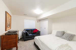 Bedroom with light colored carpet and a closet