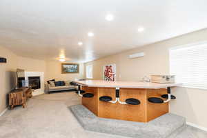 Bar area featuring light countertops, light colored carpet, a tiled fireplace, and recessed lighting