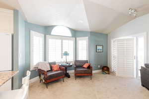 Living area with light colored carpet and vaulted ceiling