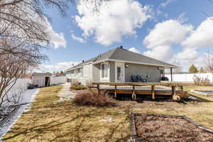 Back of property with a fenced backyard, stucco siding, a deck, a storage unit, and a shingled roof
