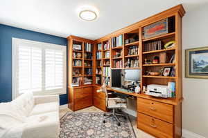 Home office with light carpet and built in desk