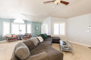 Living area featuring lofted ceiling, ceiling fan, and light carpet