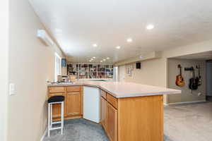 Kitchen featuring a peninsula, light countertops, light carpet, recessed lighting, and a breakfast bar area