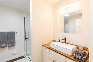 Full bath with vanity, a stall shower, and dark wood-style flooring
