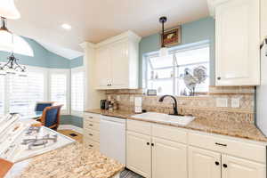 Kitchen with pendant lighting, white appliances, healthy amount of natural light, light stone countertops, and lofted ceiling