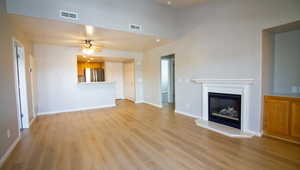 Unfurnished living room featuring a glass covered fireplace, light wood-type flooring, and a ceiling fan