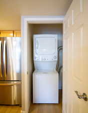Laundry area featuring stacked washing machine and dryer and light wood-style flooring