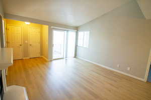 Unfurnished living room featuring lofted ceiling and light wood-style flooring