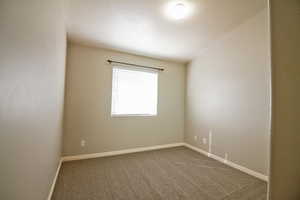 Unfurnished room featuring dark colored carpet and baseboards