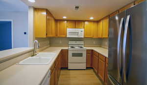 Kitchen featuring white appliances, light countertops, recessed lighting, light wood-type flooring, and wood finish cabinetry