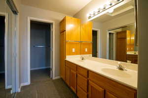 Bathroom featuring double vanity and dark colored carpet