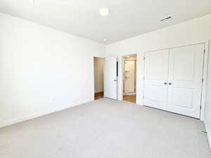 Unfurnished bedroom with ensuite bath, light carpet, and a closet