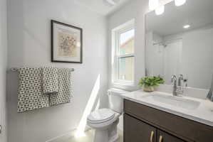 Bathroom featuring a vanity with a white countertop and undermount sink, dark wood-finish cabinetry, chrome fixtures, and a framed mirror