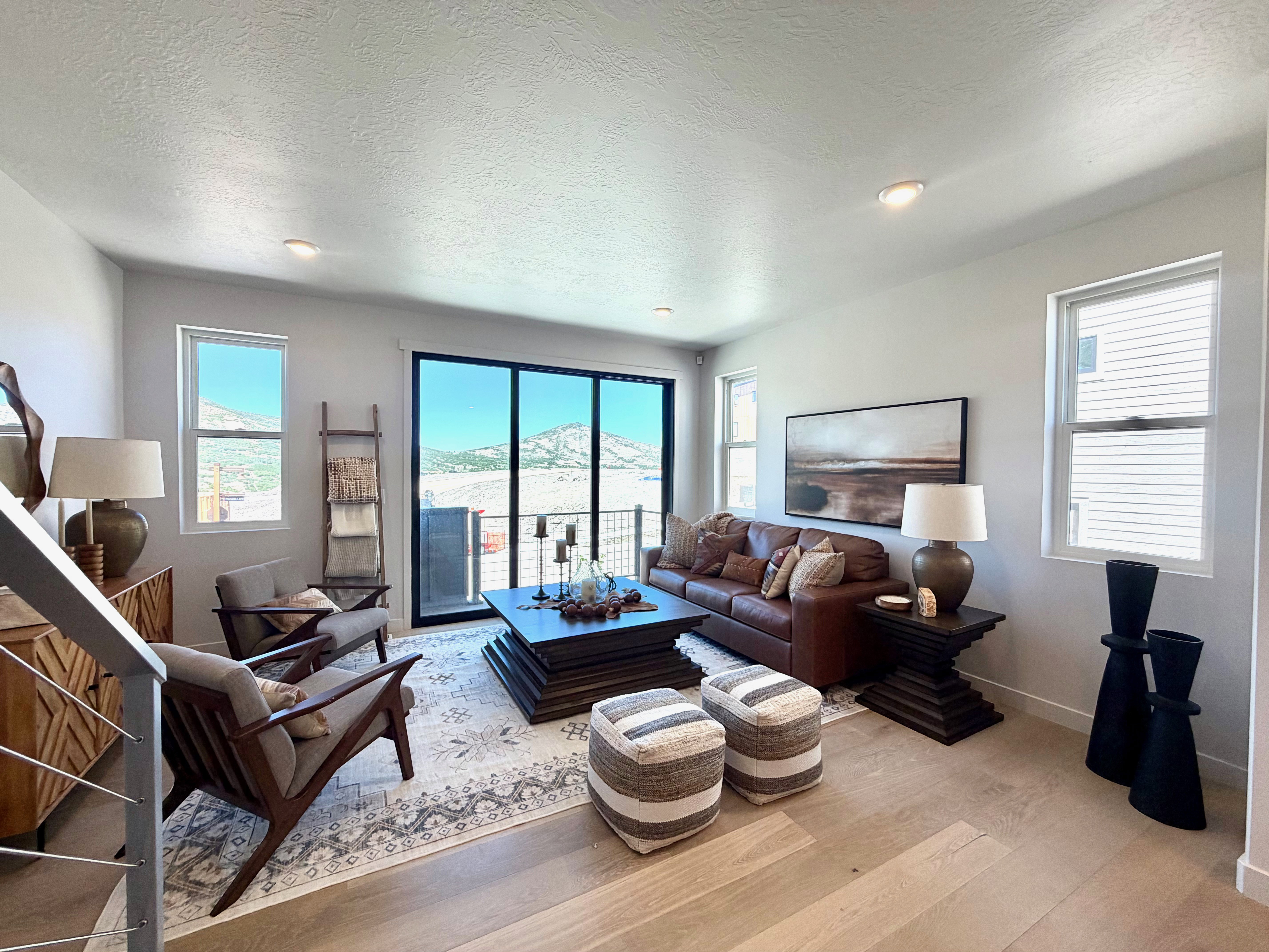 Spacious living area featuring light wood-finish flooring, recessed lighting, and large windows