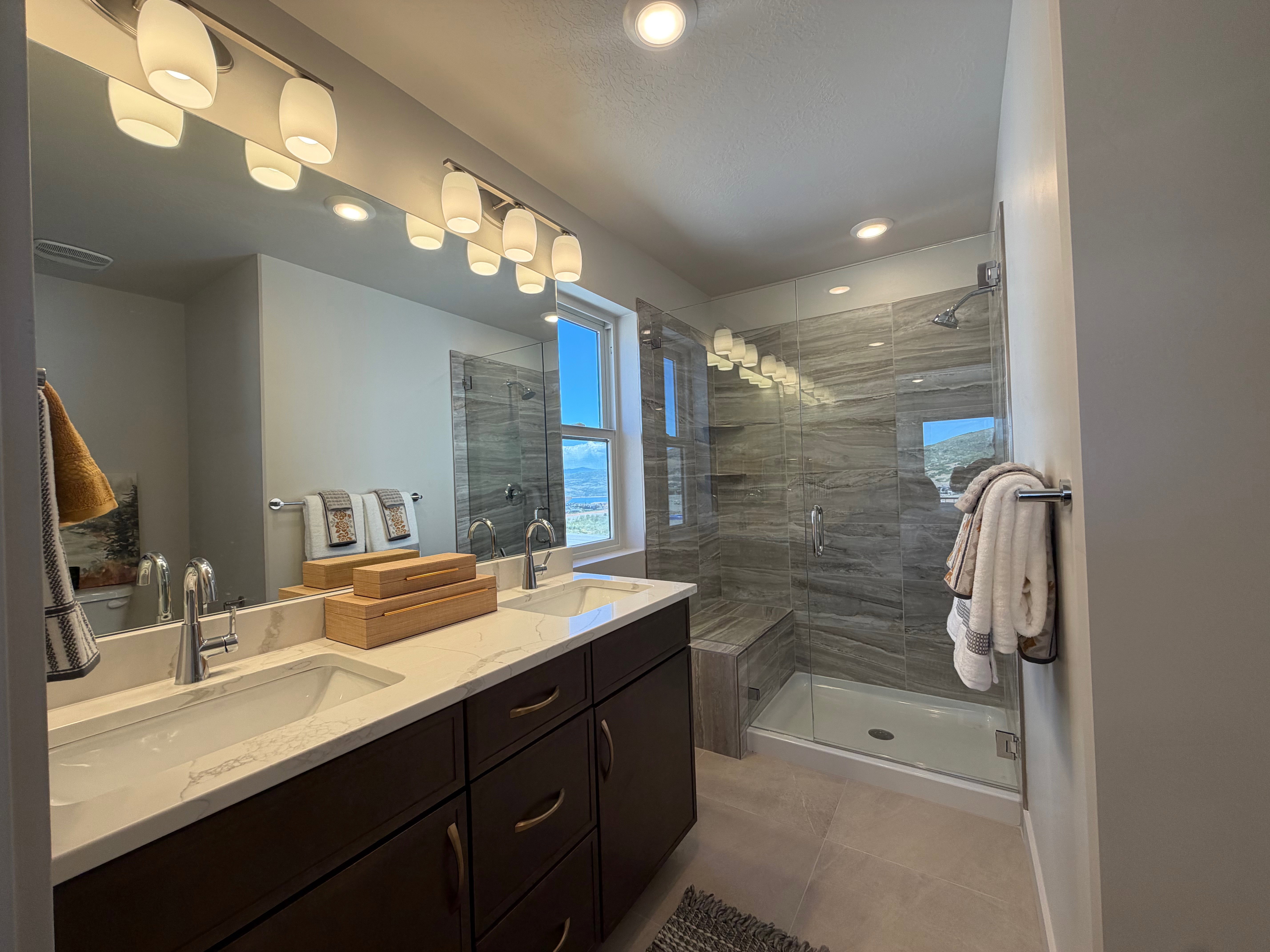 Bathroom featuring a dual vanity with undermount sinks, stone-finish countertop, and dark wood cabinetry
