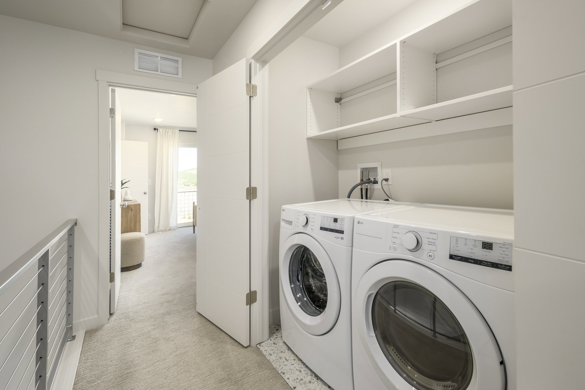 Dedicated laundry area featuring stacked appliances and open shelving