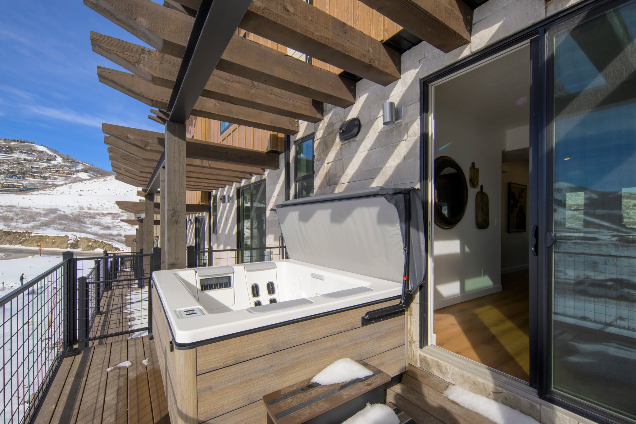 Snow covered deck featuring a hot tub, a mountain view, and a pergola