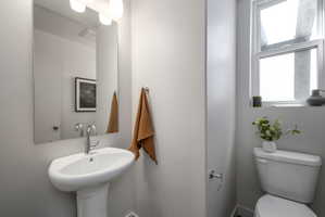 Pedestal sink with chrome faucet, large rectangular mirror, and wall-mounted vanity lighting