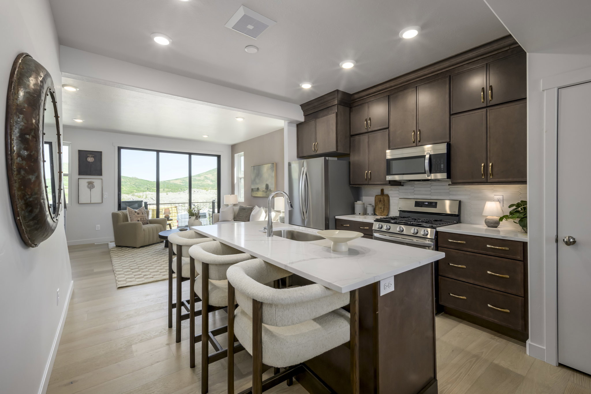 Kitchen featuring dark wood cabinetry, stainless steel appliances, a white subway tile backsplash, and a large island with white countertops