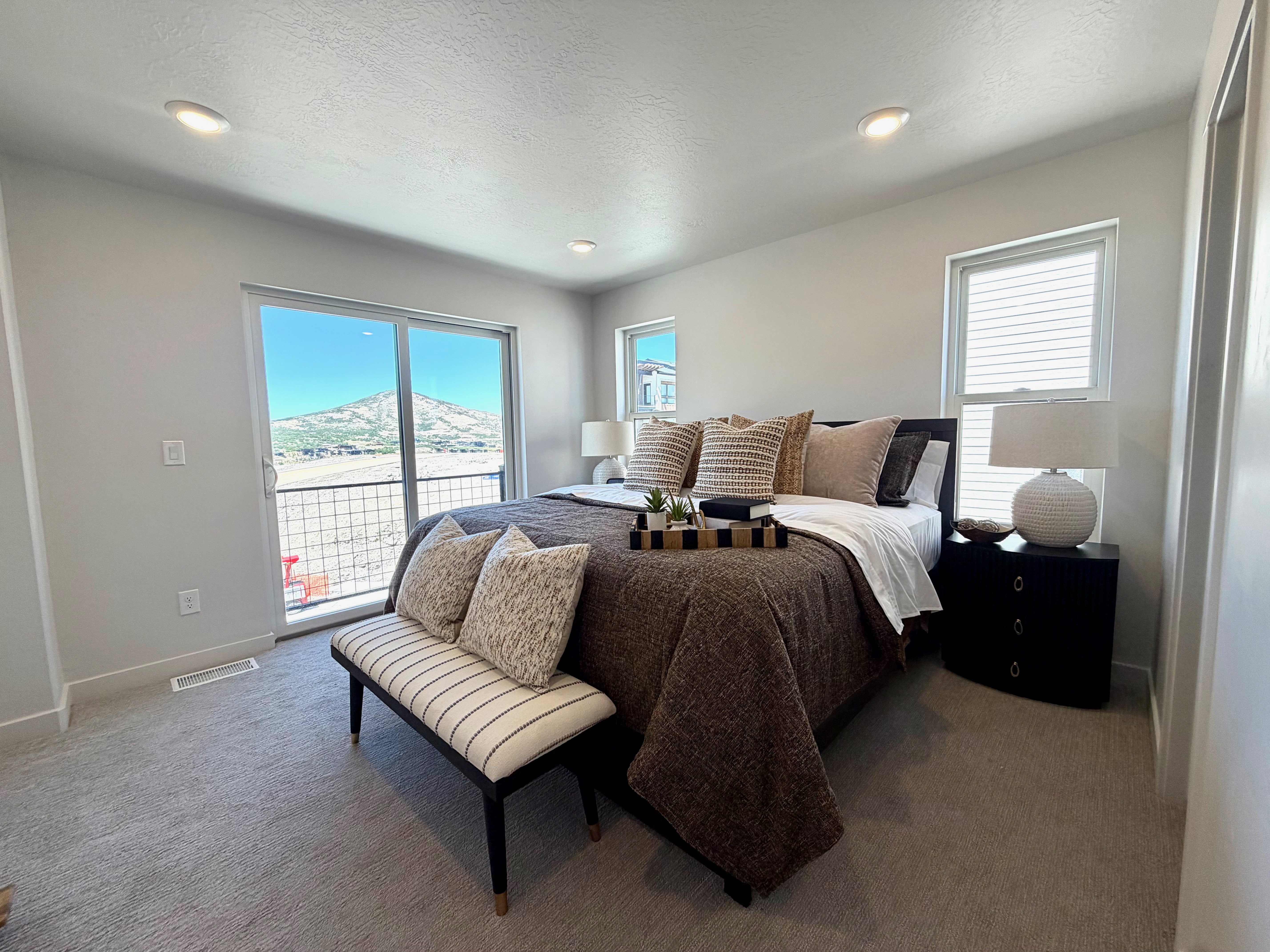 Spacious room featuring neutral carpeting, recessed lighting, and a large sliding glass door with a metal railing balcony