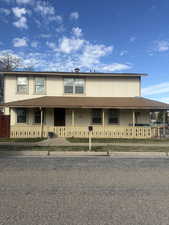 Farmhouse-style home with roof with shingles and a porch