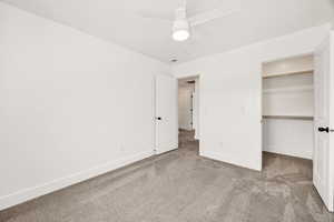 Unfurnished bedroom with a walk in closet, light carpet, and ceiling fan