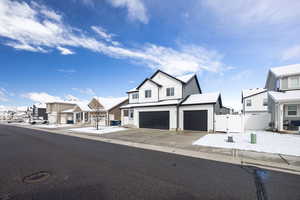 Modern farmhouse style home featuring a gate, a residential view, board and batten siding, an attached garage, and driveway