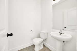 Half bathroom featuring toilet and light tile patterned floors