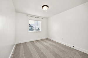 Spare room with baseboards and light carpet
