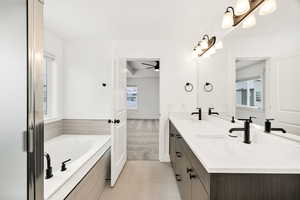 Bathroom featuring double vanity, a garden tub, light tile patterned flooring, and light colored carpet