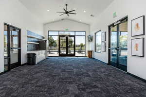 Clubhouse with french doors, dark colored carpet, ceiling fan, a high ceiling, and recessed lighting
