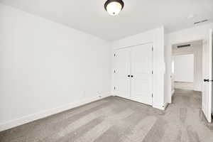 Unfurnished bedroom featuring light carpet and a closet