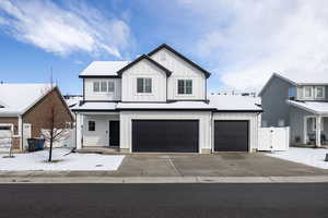 Modern farmhouse with board and batten siding, covered porch, driveway, a gate, and an attached garage