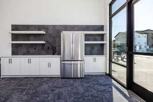 Kitchen featuring open shelves, freestanding refrigerator, white cabinets, and dark carpet