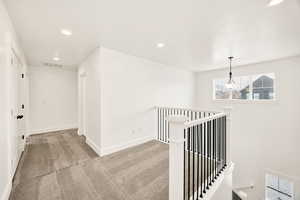 Hallway featuring carpet floors, an upstairs landing, and recessed lighting