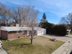 View of side of property featuring driveway, a yard, and brick siding
