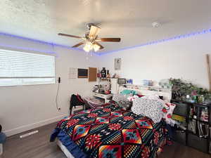 Bedroom featuring a textured ceiling, dark wood-style floors, and ceiling fan