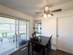 Dining room featuring dark wood-style floors, a ceiling fan, and a textured ceiling