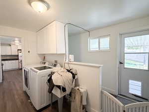 Laundry area with separate washer and dryer, cabinet space, and dark wood-type flooring